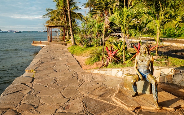 Sidewalk along Canto Beach in Buzios, Brazil with a bronze statue and ocean view.