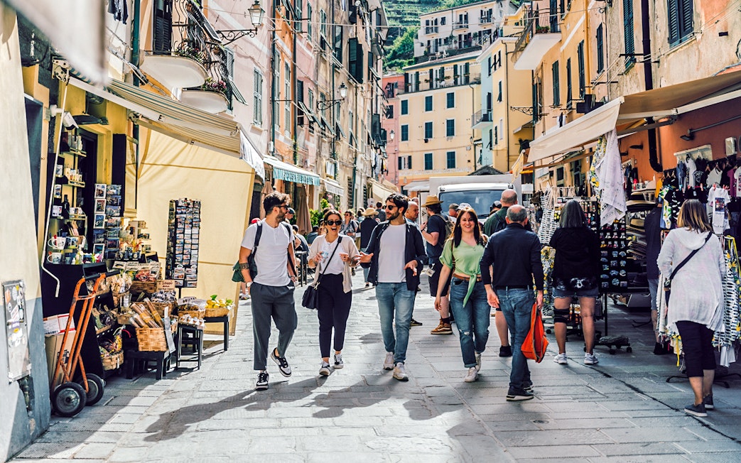 Visitors walking through a bustling street market in Cinque Terre, Italy.