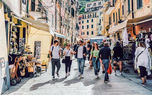 Visitors walking through a bustling street market in Cinque Terre, Italy.