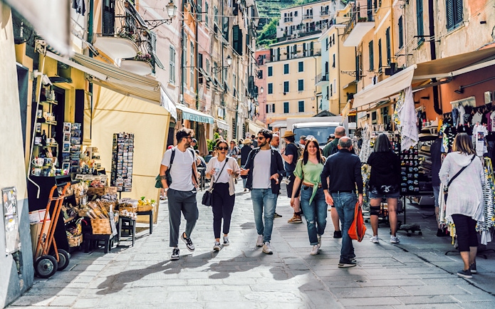 Visitors walking through a bustling street market in Cinque Terre, Italy.