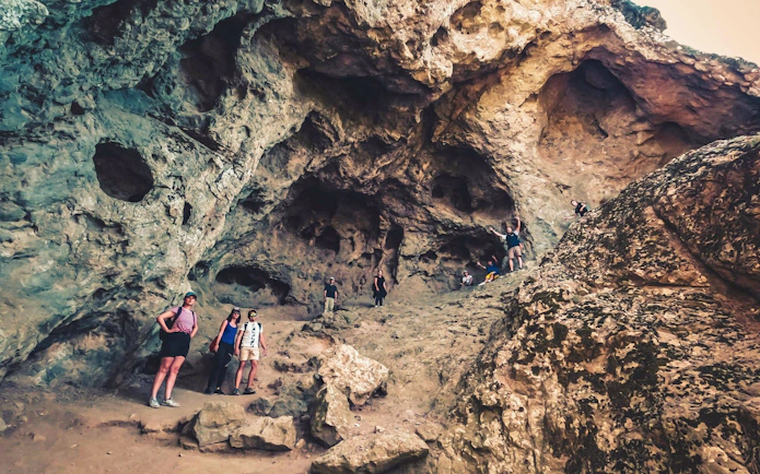 Tourists exploring volcanic rock formations in Gran Canaria during sunset tour.