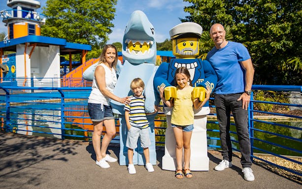 Family posing with LEGO shark and sailor figures at LEGOLAND Windsor Resort.
