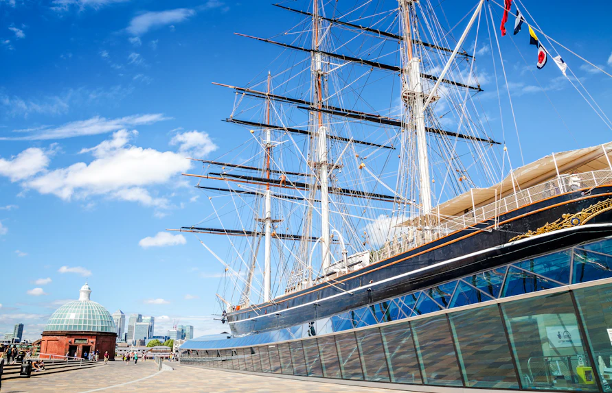 Cutty Sark ship in Greenwich, London, with city skyline in the background.