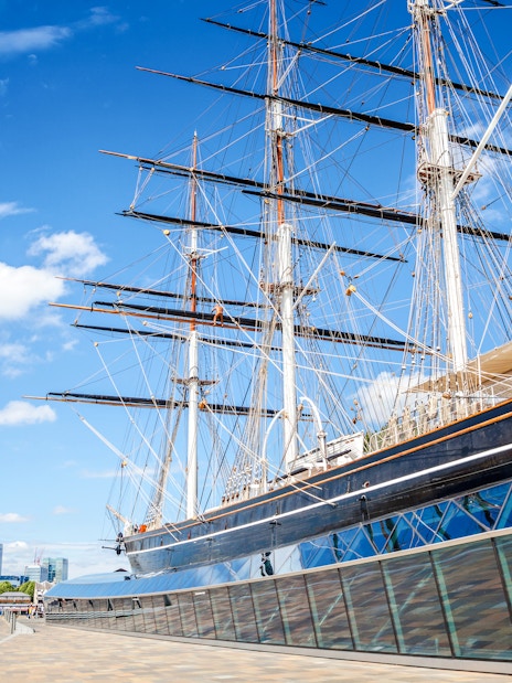 Cutty Sark ship in Greenwich, London, with city skyline in the background.