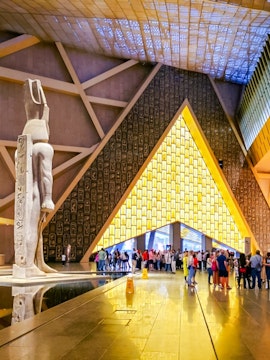 Main atrium of the Grand Egyptian Museum with statue and visitors, Cairo day trip from Hurghada.