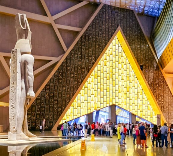 Main atrium of the Grand Egyptian Museum with statue and visitors, Cairo day trip from Hurghada.