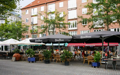 Outdoor cafes in St. Georg, Hamburg, with people dining under umbrellas.