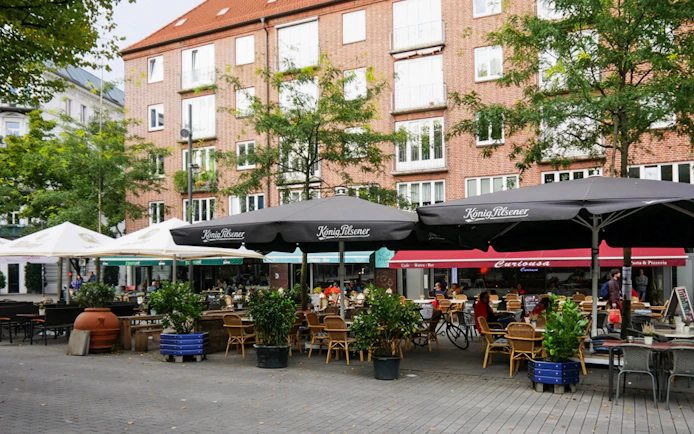 Outdoor cafes in St. Georg, Hamburg, with people dining under umbrellas.
