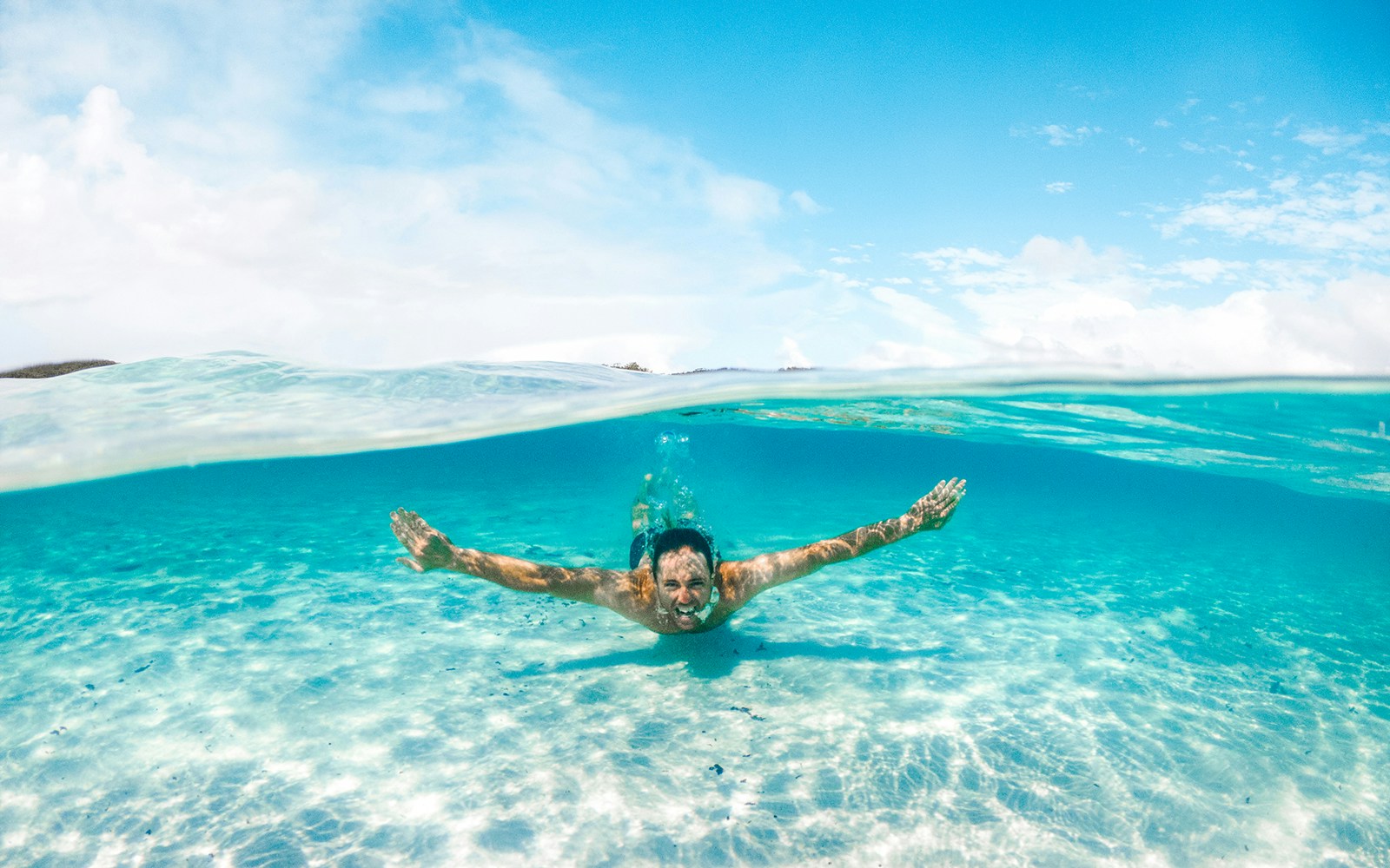 Man swimming underwater in clear creek.
