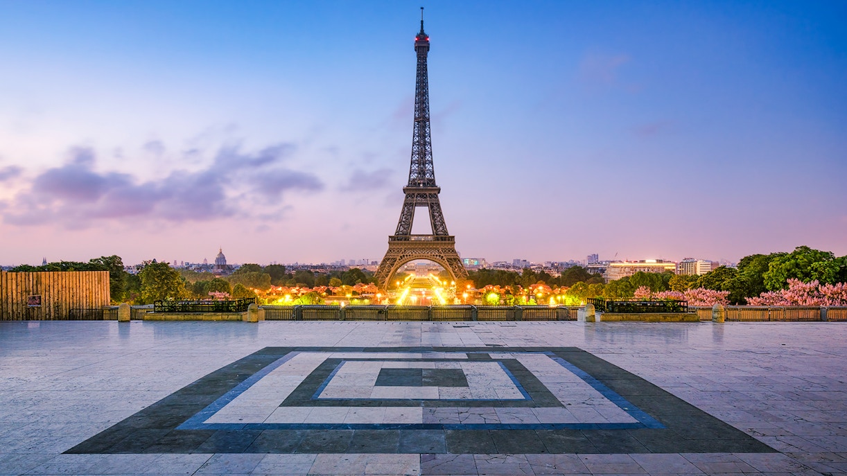 Eiffel Tower illuminated at dusk in Paris, France, viewed from Trocadéro Gardens.