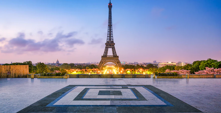 Eiffel Tower illuminated at dusk in Paris, France, viewed from Trocadéro Gardens.