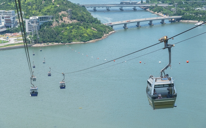 Ngong Ping Cable Car over water with lush hills and bridges in Hong Kong.