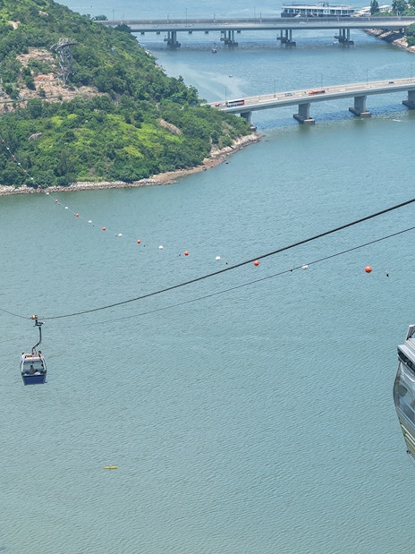 Ngong Ping Cable Car over water with lush hills and bridges in Hong Kong.