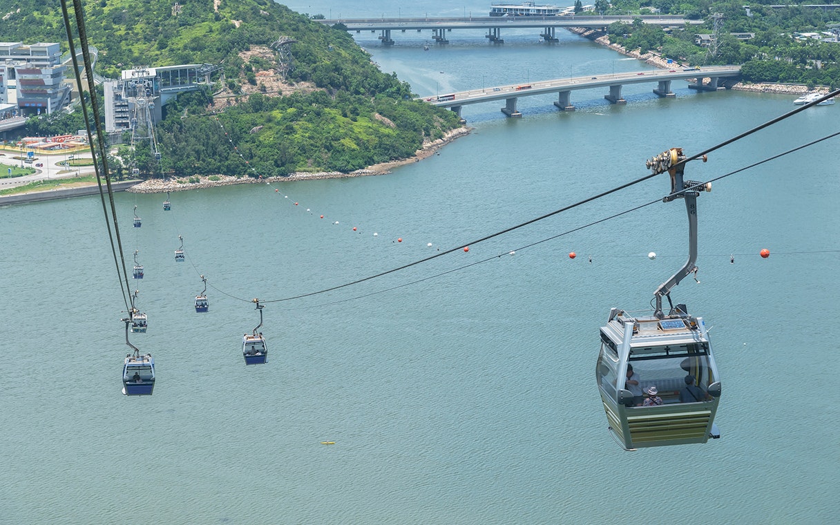 Ngong Ping Cable Car over water with lush hills and bridges in Hong Kong.
