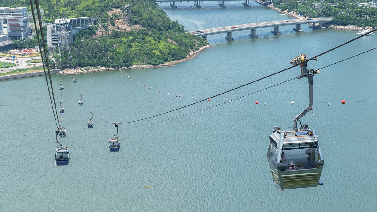 Ngong Ping Cable Car over water with lush hills and bridges in Hong Kong.