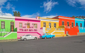 Colorful houses in Bo-Kaap, Cape Town, with vibrant facades and parked cars.