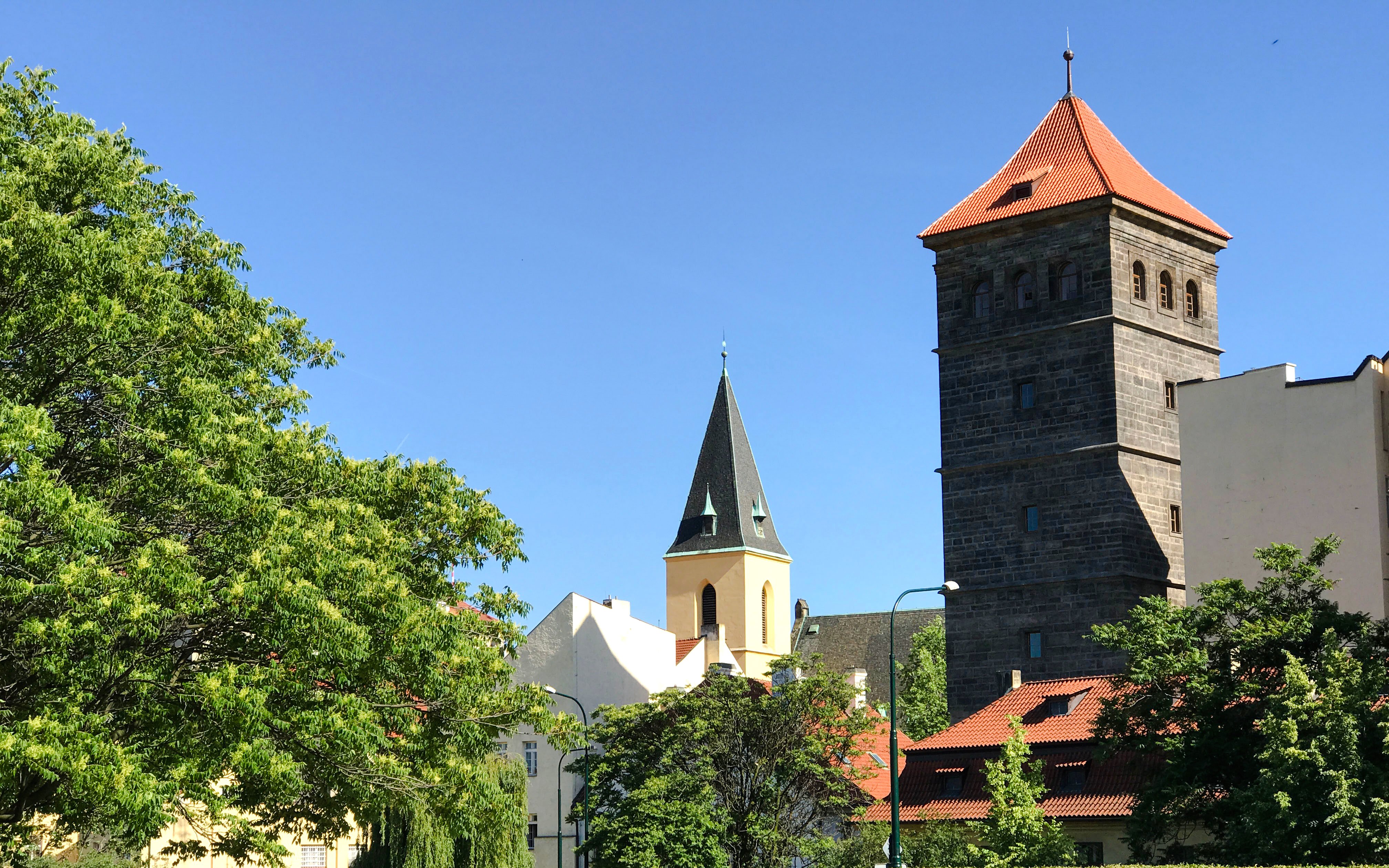 New Mill Water Tower and church spire surrounded by trees in Prague.