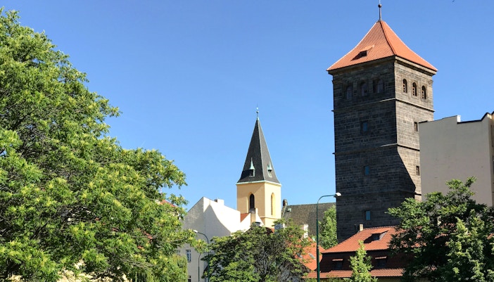 New Mill Water Tower and church spire surrounded by trees in Prague.