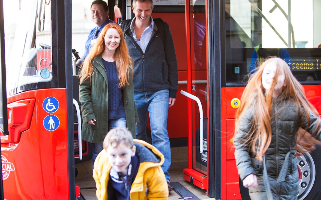 Passengers exiting a red bus during Edinburgh Hop-On Hop-Off Tour.