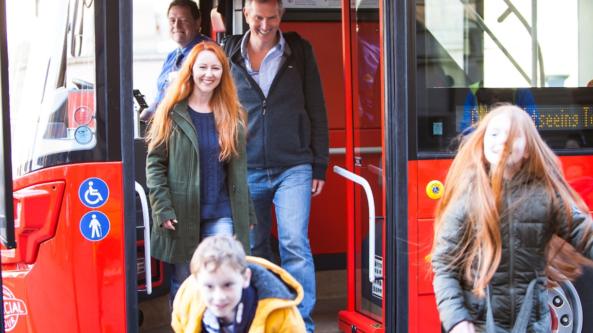 Double-decker bus on Edinburgh Hop-On Hop-Off Tour passing historic buildings in Edinburgh, Scotland.