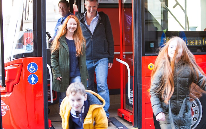 Passengers exiting a red bus during Edinburgh Hop-On Hop-Off Tour.