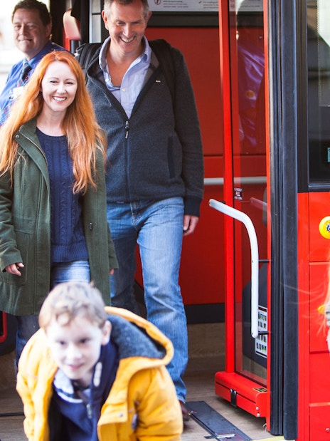 Passengers exiting a red bus during Edinburgh Hop-On Hop-Off Tour.