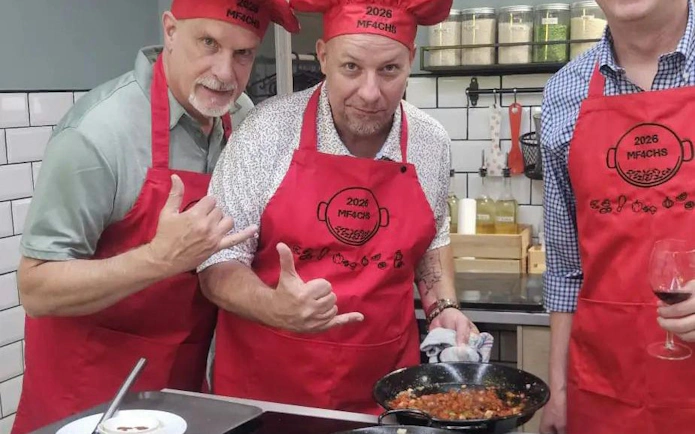 Participants in a cooking class preparing paella in Barcelona kitchen.