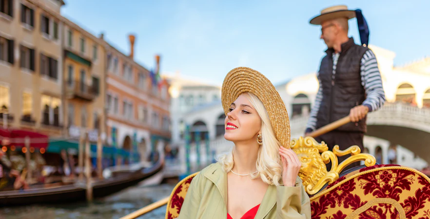 Gondola ride on Venice canal with Rialto Bridge in background.