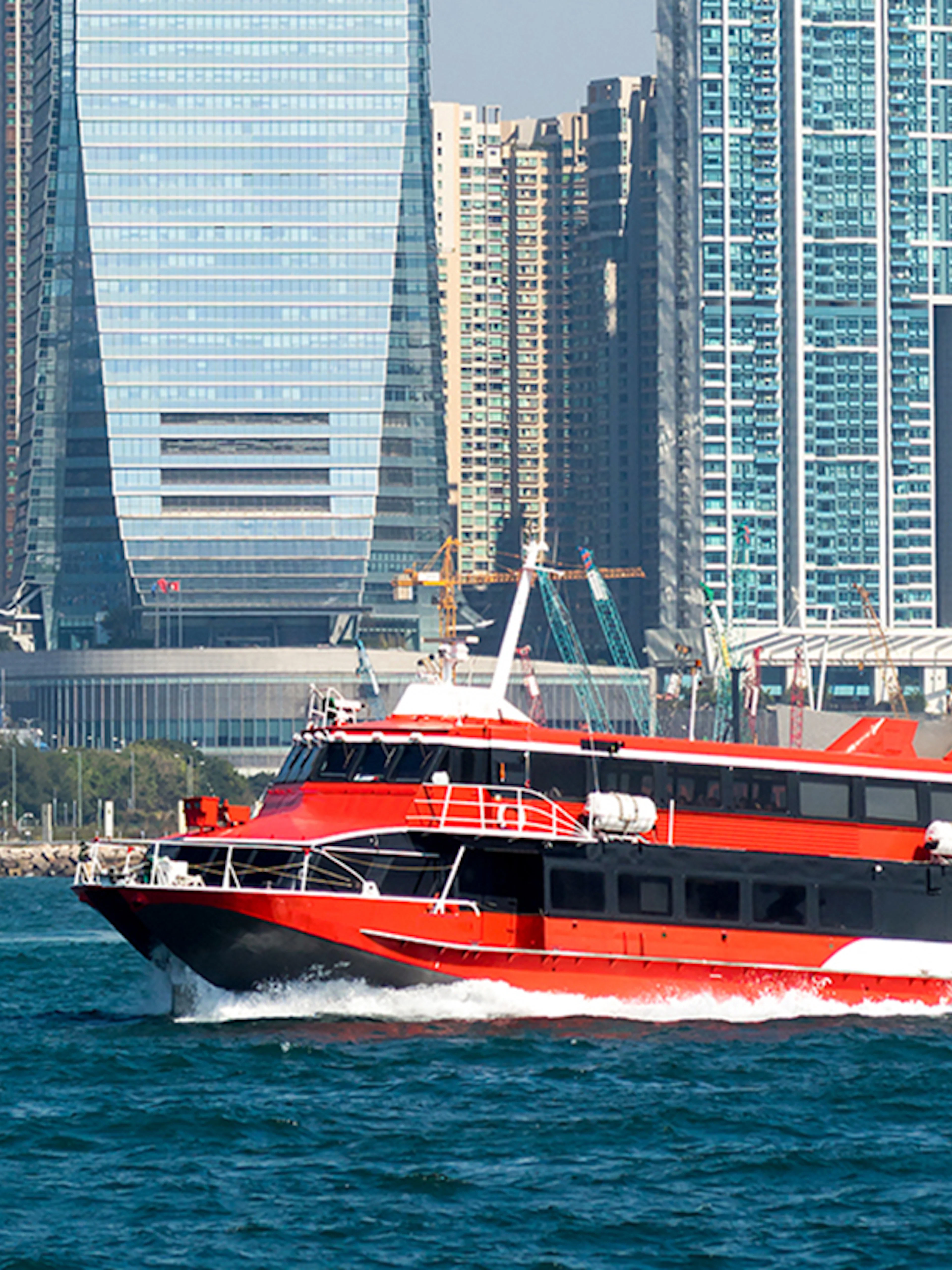 Ferry cruising in Hong Kong harbor with city skyline in the background.