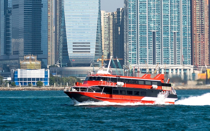 Ferry cruising in Hong Kong harbor with city skyline in the background.