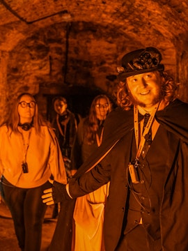 Tour guide leading Edinburgh Ghost Tour in underground vaults.