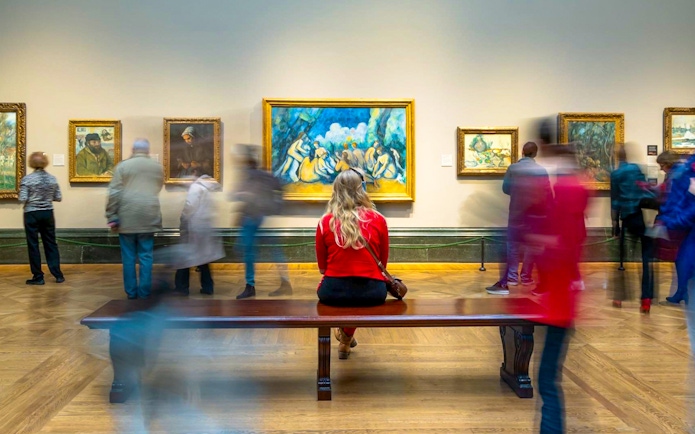 Woman sitting on bench viewing artwork at National Gallery guided tour.