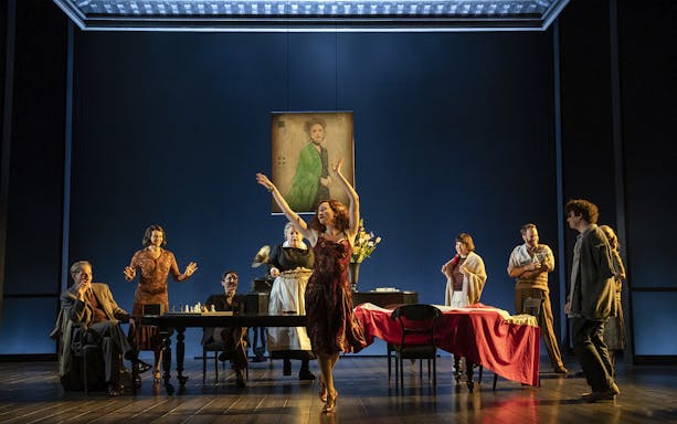 Theater scene from Leopoldstadt with actors around a table and a woman dancing.