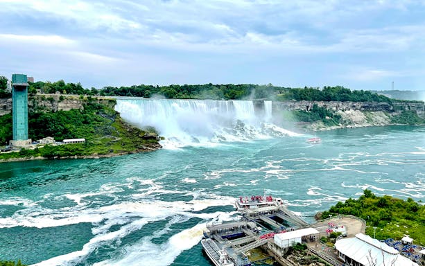 Niagara Falls view with observation tower and tour boat on Ontario, Canada border.