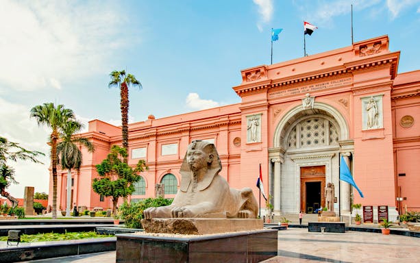 Egyptian Museum in Cairo with sphinx statue in foreground.