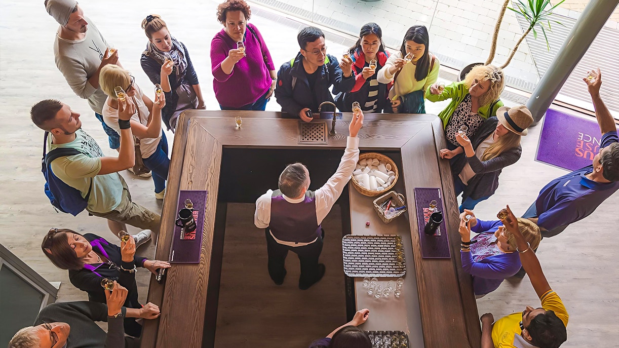 Tour group tasting whisky at a distillery bar in Edinburgh.