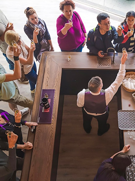 Tour group tasting whisky at a distillery bar in Edinburgh.