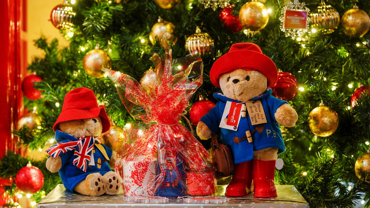 Paddington Bear toys by a decorated Christmas tree in London.