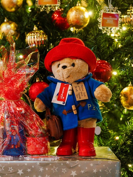 Paddington Bear toys by a decorated Christmas tree in London.
