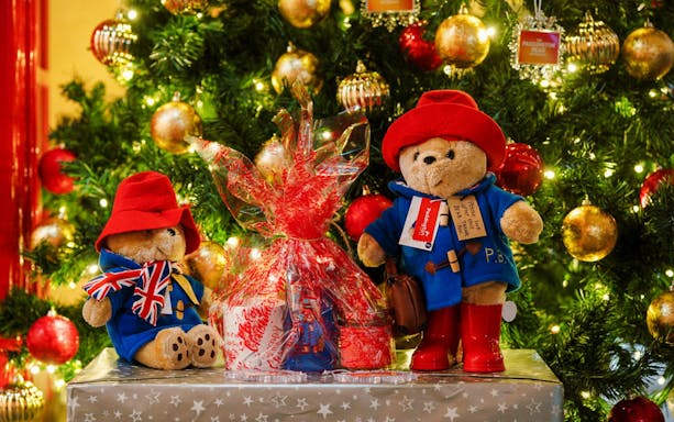 Paddington Bear toys by a decorated Christmas tree in London.