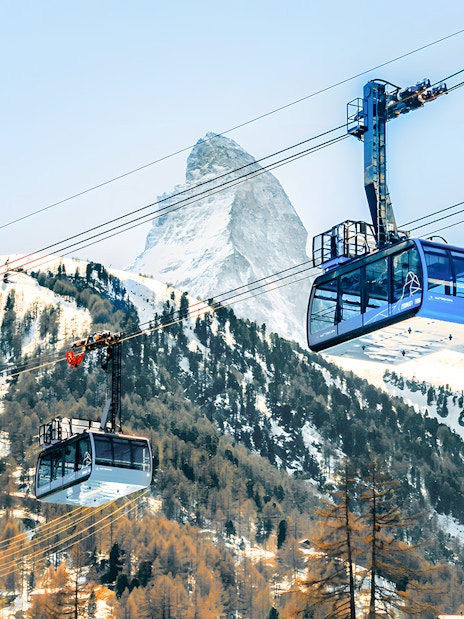 Cable cars ascending to Matterhorn Glacier Paradise with snowy mountain backdrop.
