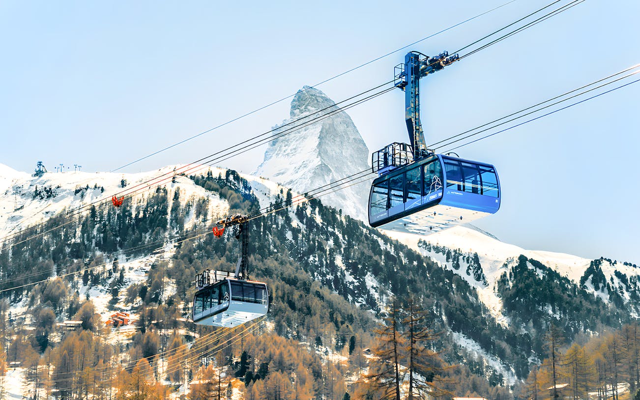 Cable cars ascending to Matterhorn Glacier Paradise with snowy mountain backdrop.