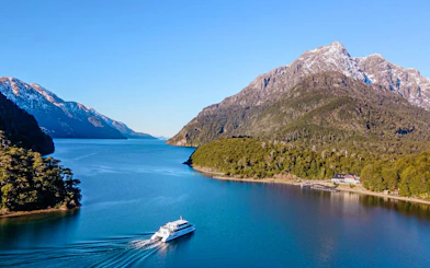 Cruise boat on Nahuel Huapi Lake with Patagonian mountains in the background.