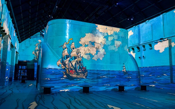 Sailing ship projection on blue walls at Fabrique des Lumières.