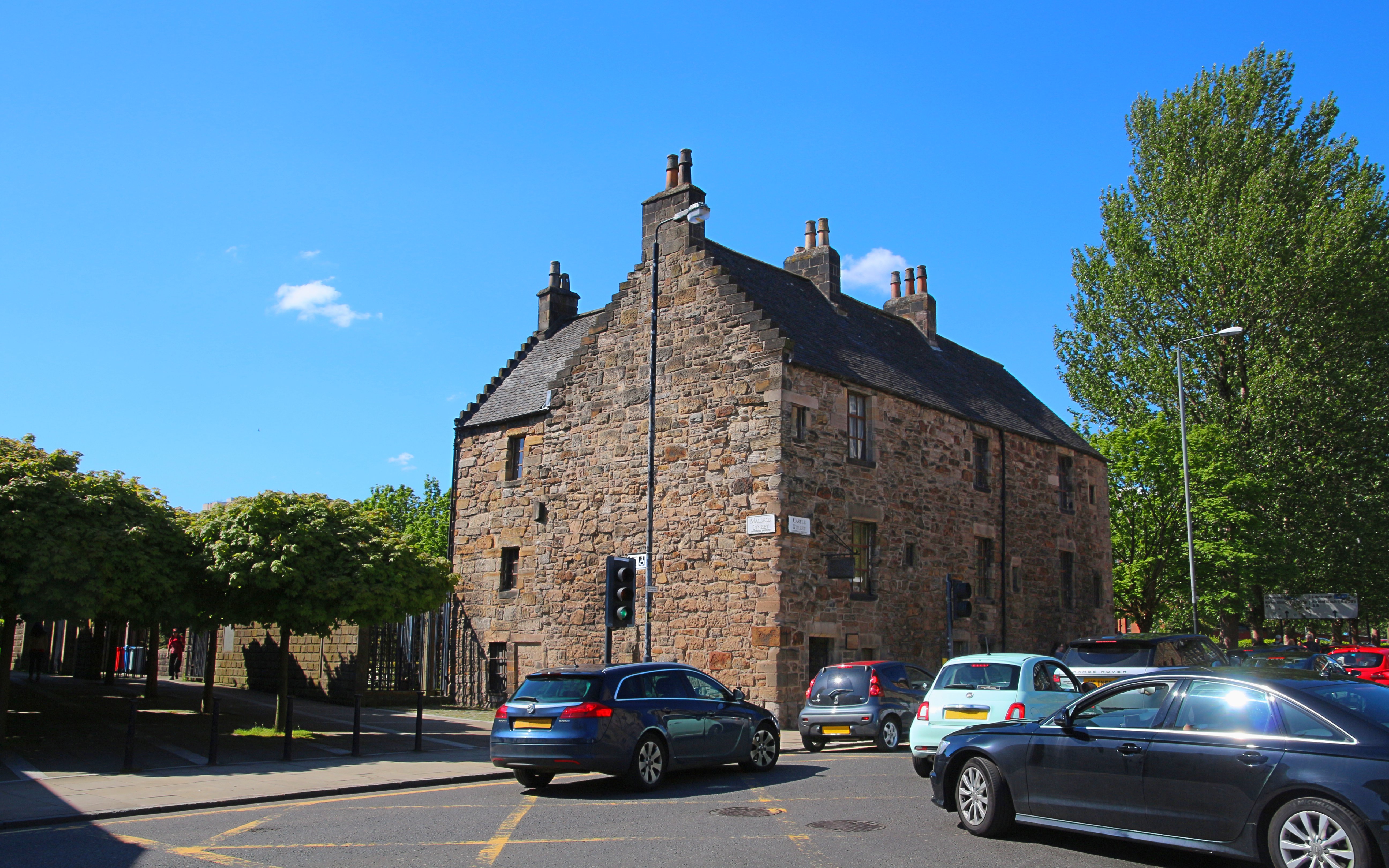 Provand's Lordship, historic stone building in Glasgow, with cars and trees nearby.