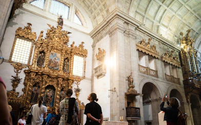 Tourists with guide admiring ornate altar in Monastery of São Bento da Vitória.