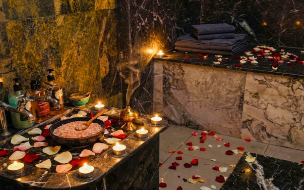 Traditional Moroccan hammam with rose petals, candles, and massage oils.