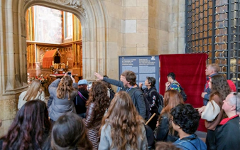Tour group exploring Prague Castle interior with guide explaining historical details.