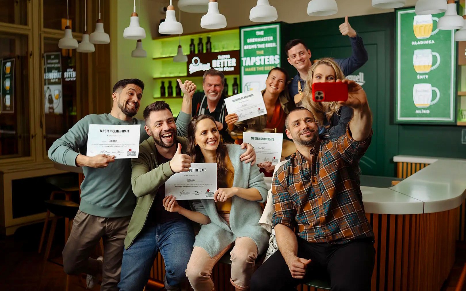 Group holding certificates at Prague Pilsner Urquell Experience bar.