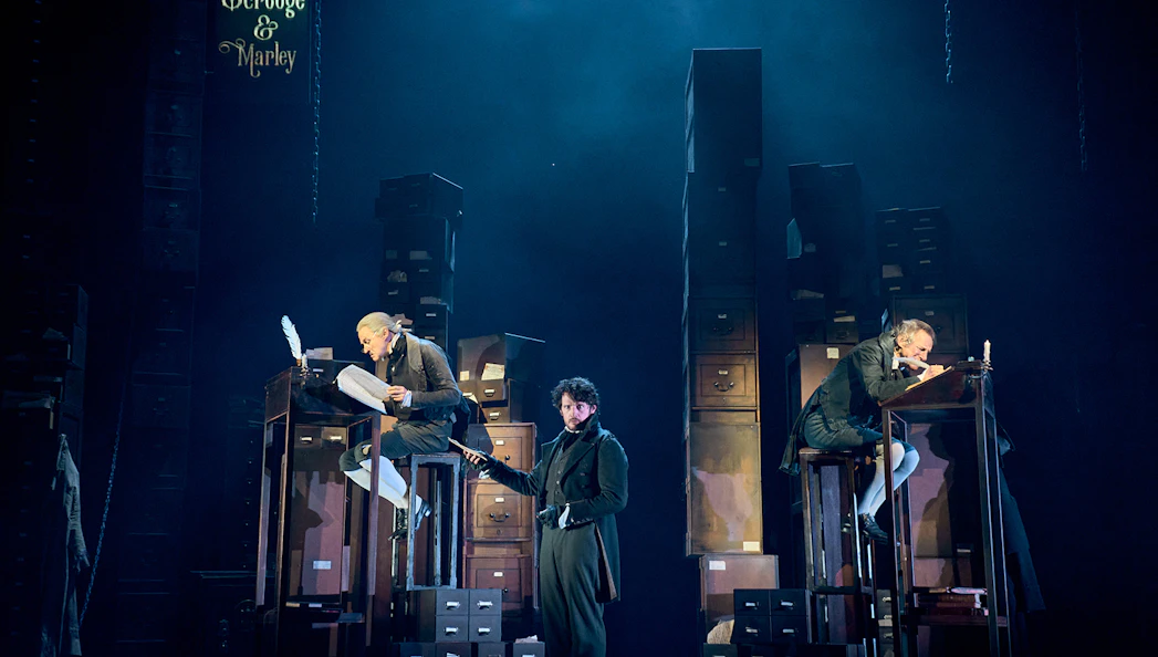 Stage scene from "A Christmas Carol - A Ghost Story" with actors in Victorian attire.